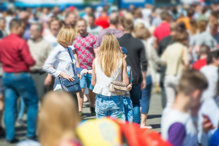 Crowd of people walking on city street with young woman with long hair in centreの写真素材