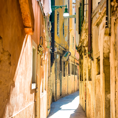 Old narrow street with brick houses in Venice, Italyの写真素材