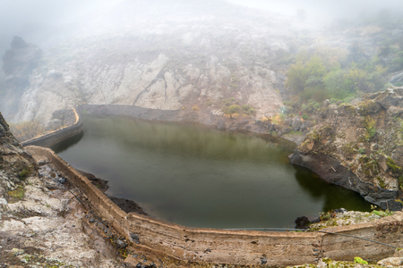 Nature mountain landscape of Canary Island with rocks and lake enveloping by dense fogの写真素材