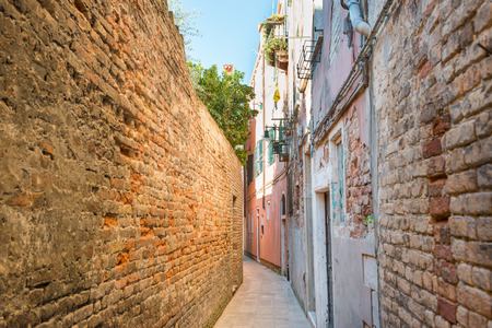 Old narrow street with brick houses in Venice, Italyの写真素材