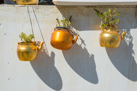 Old rustic copper kettles with plants hanging on white wall. Souq Waqif market, Doha, Qatarの写真素材