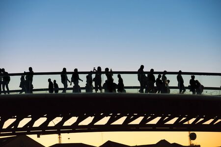 Silhouette of walking people on bridge at sunsetの写真素材