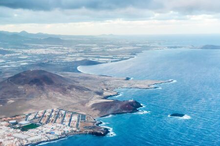 Airplane aerial view of coastal landscape and town oÐ° Arinaga on Gran Canaria island with ocean, hills and citiesの写真素材