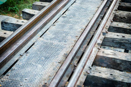 Rail track with wooden sleepers and rusty rails at old railway bridgeの写真素材