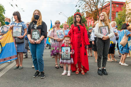 KIEV, UKRAINE - AUGUST 24, 2020: Girl with portrait of her killed in war farther on March of defenders, parade in Kyiv, dedicated to the Independence Day of Ukraine, 29th anniversary.のeditorial素材