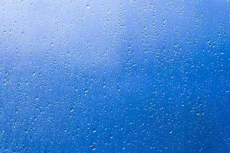 Rain water drops pattern on blue window glass surfaceの写真素材