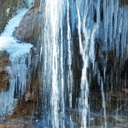 Spring water stream from melted snow, ice and iciclesの写真素材