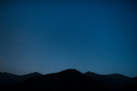Silhouette of mountain range under dark blue night sky with many bright starsの写真素材