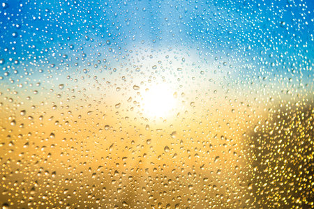 Beautiful sunset through a spattered glass with water rain dropsの写真素材