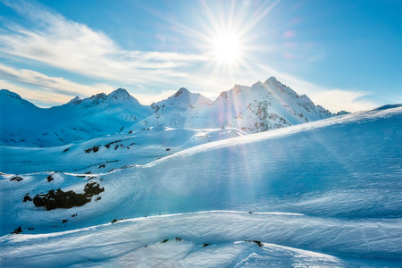 Sunset in winter mountains covered by snow. Shining sun on the blue skyの写真素材