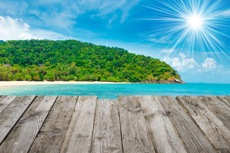 Green island with beach and green montain, view from wooden tableの写真素材