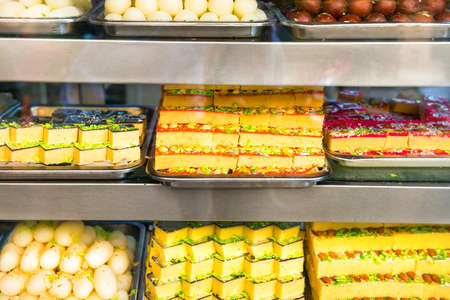 Many delicious traditional indian sweets and desserts at storefront at asian food marketの写真素材