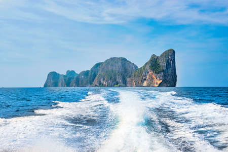 Phi Phi island landscape panorama in Thailand with white waves stream behind speed boat, sea and mountainsの写真素材