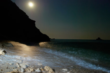 Moon night on the sea with waves and rocks.の写真素材