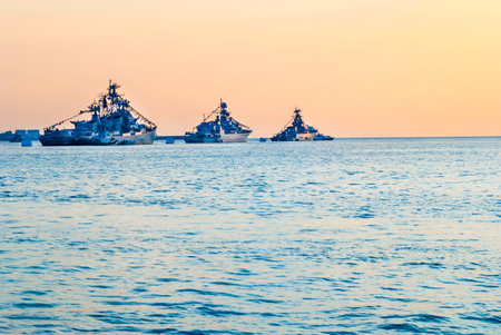 Military navy ships warships in sea bay at sunsetの写真素材