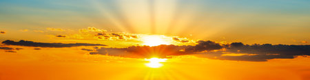 Sunset dramatic sky panorama background with sun and sunset cloudsの写真素材