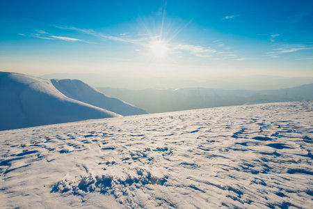 Winter mountain landscape with snow mountains and sun on blue skyの写真素材