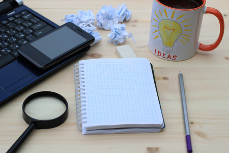 On the desktop - laptop, mobile phone, notebook and pencils. a cup of coffee, close-upの写真素材