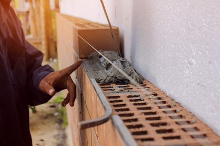 Bricklayer lays bricks under unravel. construction workの写真素材