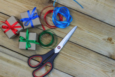 Scissors, gift boxes and  ribbons on a wooden table.の写真素材