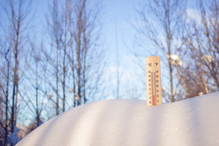Thermometer in snow, the picture was taken from below on a blue sky background