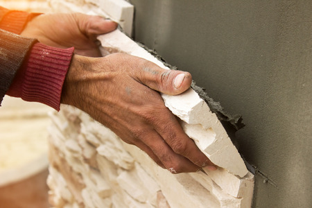 Builder puts a wall house made of artificial stoneの写真素材