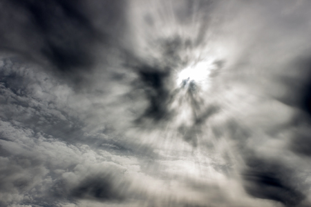 Through black and white clouds the sun shining bright raysの写真素材