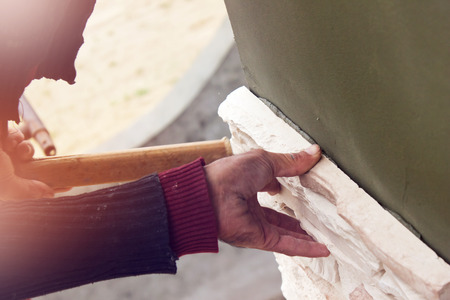 Builder puts a wall house made of artificial stoneの写真素材