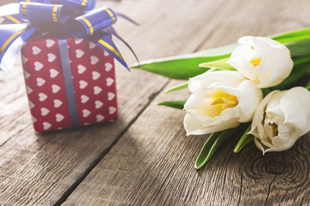 White tulips and gift box on wooden tableの写真素材
