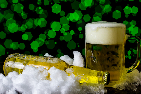 Bottle and beer mug in the snow on bokeh backgroundの写真素材