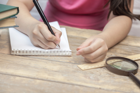 Young student writes the lessons in a notebookの写真素材