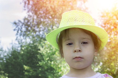 Little girl in a hat on the nature close upの写真素材