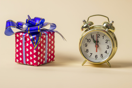 Golden watch and a gift on a light brown backgroundの写真素材
