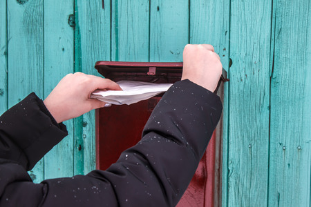 The person takes out letters from the mailbox