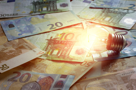 Glowing light bulb on a background of money