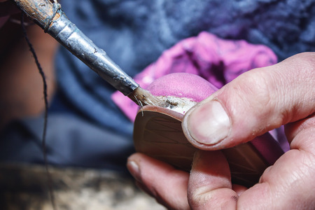 Young shoemaker glues shoes