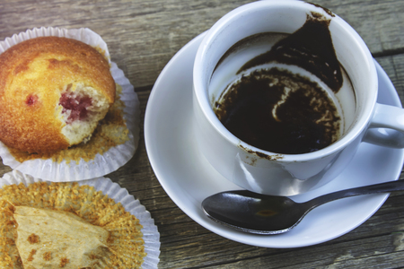 A Cup finished of coffee with a bitten cake, close-upの写真素材