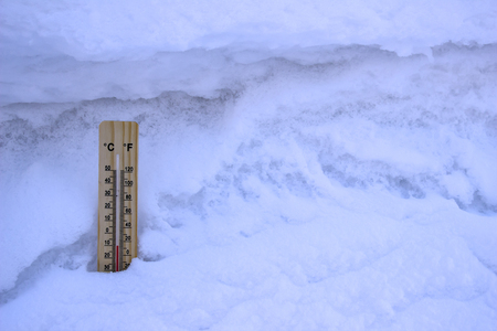 Thermometer inserted into the white snow, close-up