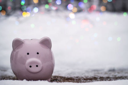 Pink piggy bank on the background of snow and bright lightsの写真素材