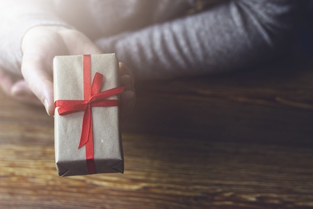 A woman passes a gift box with a red ribbon