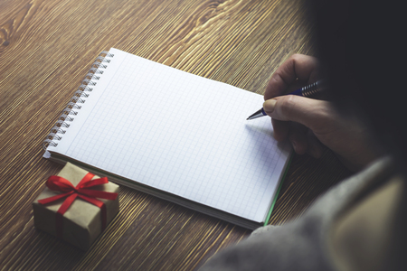 A woman wants to write in an empty notebook, which lies next to the gift boxの写真素材