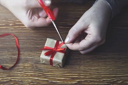 Woman cuts a red bow on a gift boxの写真素材