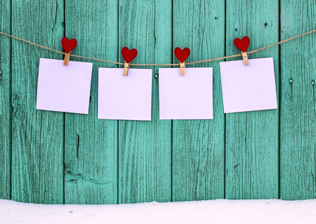 Four empty photos hanging on a rope clothespins with a heartの写真素材