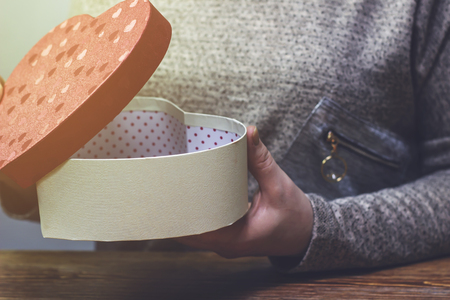 A woman opens a gift with joyの写真素材