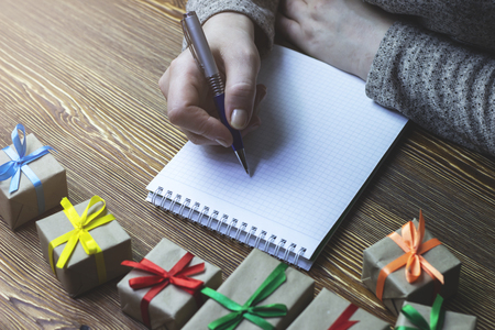 A woman makes a note in a notebook that lies on a wooden table, front viewの写真素材