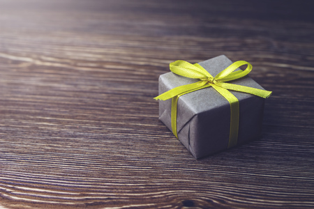Gift box with yellow ribbon lying on a wooden tableの写真素材