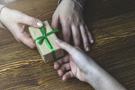 Girl gives a woman a gift box with a green ribbonの写真素材
