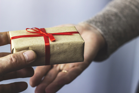 A man gives a woman a gift with a red ribbonの写真素材