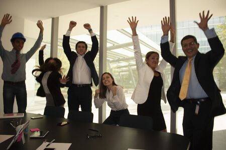 Co-workers in the office jumping for happiness because they have managed to close a contract in Mexico Cityの写真素材
