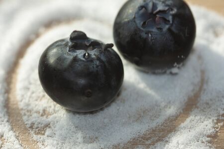 Sugar substitute granules with a simulated heart wrapping a pair of blueberries to develop sugar-free dessertsの写真素材
